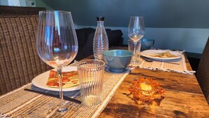 A dining table with a plate of food, two wine glasses, a glass of water, a blue bowl, and a decorative candle. - Apartment -Sorayas Welt- direkt hinter dem Deich mit allen Annehmlichkeiten (Neufeld)