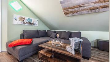 En moderne stue med en grå modulsofa, et træsofabord og et billede på væggen.