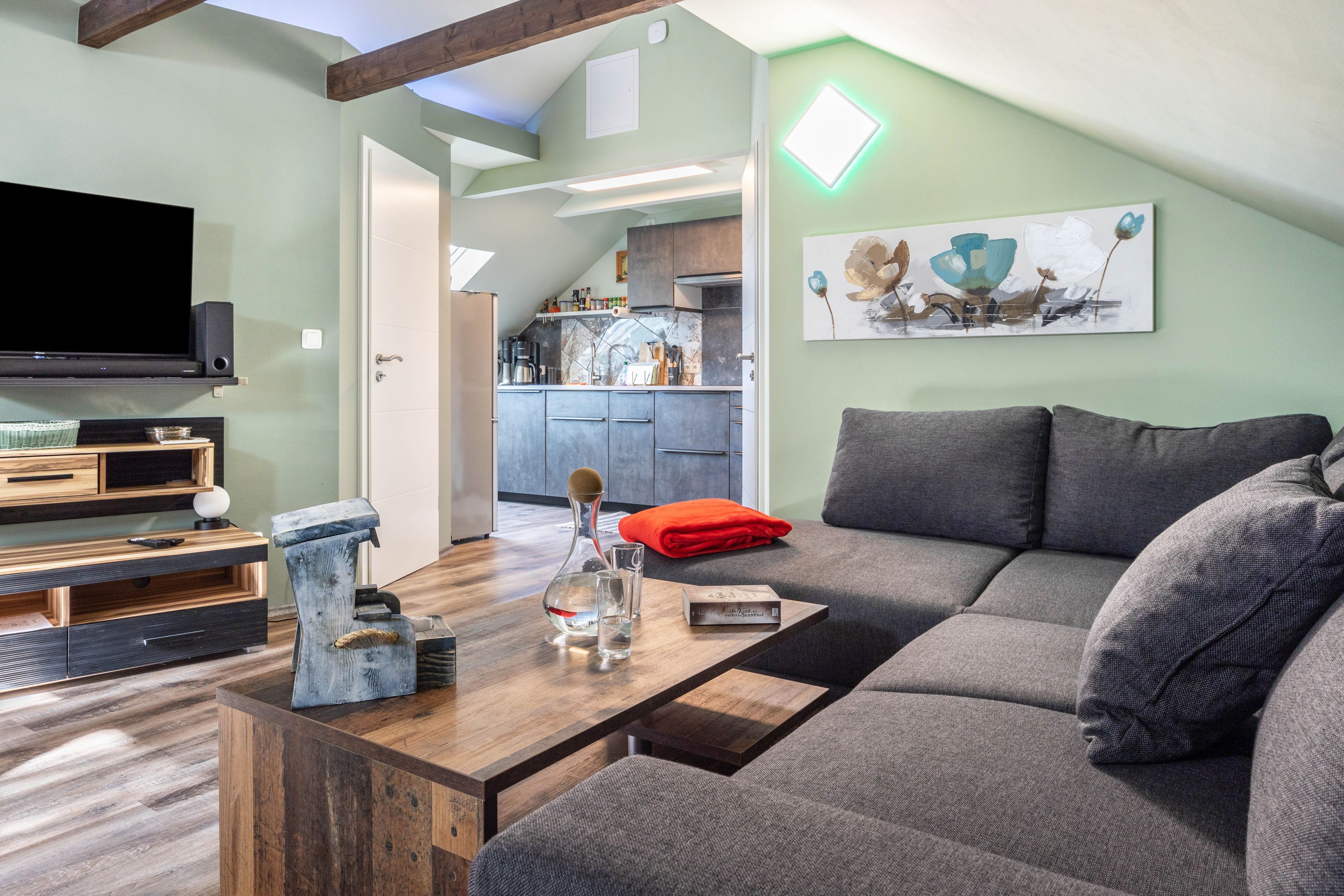 Una sala moderna con un sofá modular, una mesa de centro de madera y un televisor de pantalla plana.