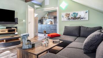 Una sala moderna con un sofá modular, una mesa de centro de madera y un televisor de pantalla plana.