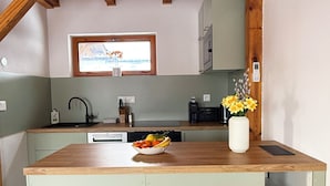 Cucina con piano di lavoro in legno, una ciotola di frutta, un vaso con fiori e una finestra vista.