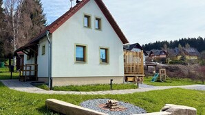 Una casa a due piani con tetto spiovente, un piccolo portico e un’area giochi recintata.