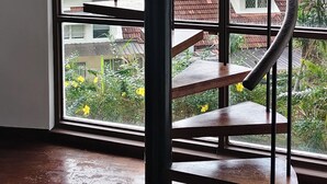 A spiral staircase with a metal frame and wooden steps, leading to a balcony with a view of the sea and buildings. - VELAMUNDI INN (George Town)
