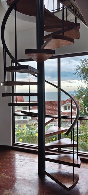 A spiral staircase with a metal frame and wooden steps, leading to an upper floor.