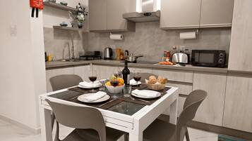 Una cocina moderna con una mesa de comedor para dos personas, equipada con un microondas, tostadora y varios electrodomésticos de cocina.