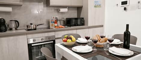 Eine moderne Küche mit Mikrowelle, Toaster und Kaffeemaschine. Ein Esstisch ist gedeckt mit Tellern, Gläsern und einer Schüssel mit Obst.