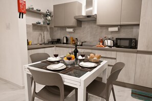 Una cocina moderna con una mesa de comedor para dos personas, equipada con un microondas, tostadora y varios electrodomésticos de cocina.