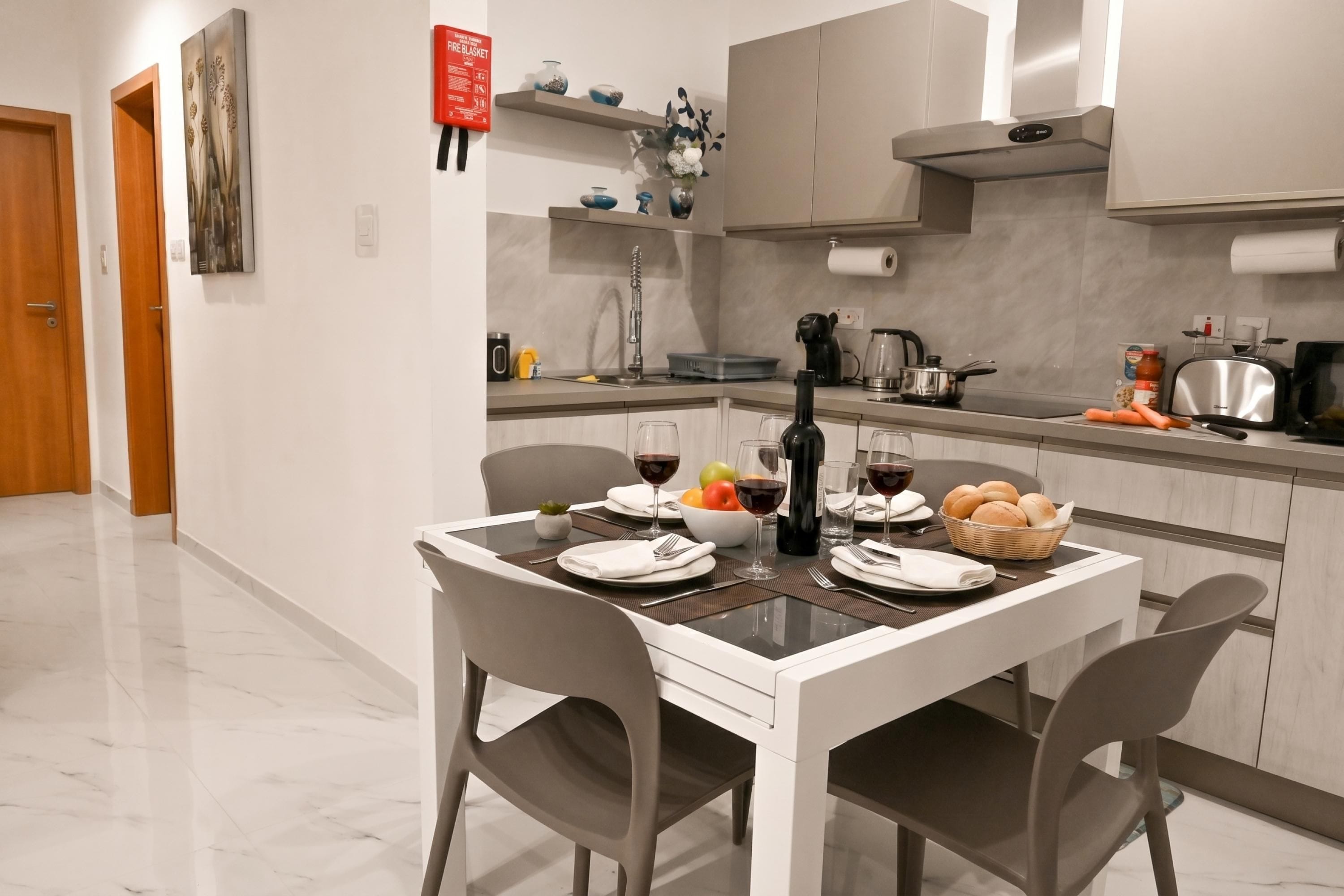 Una cocina moderna con una mesa de comedor preparada para dos personas, una cafetera y un tostador.