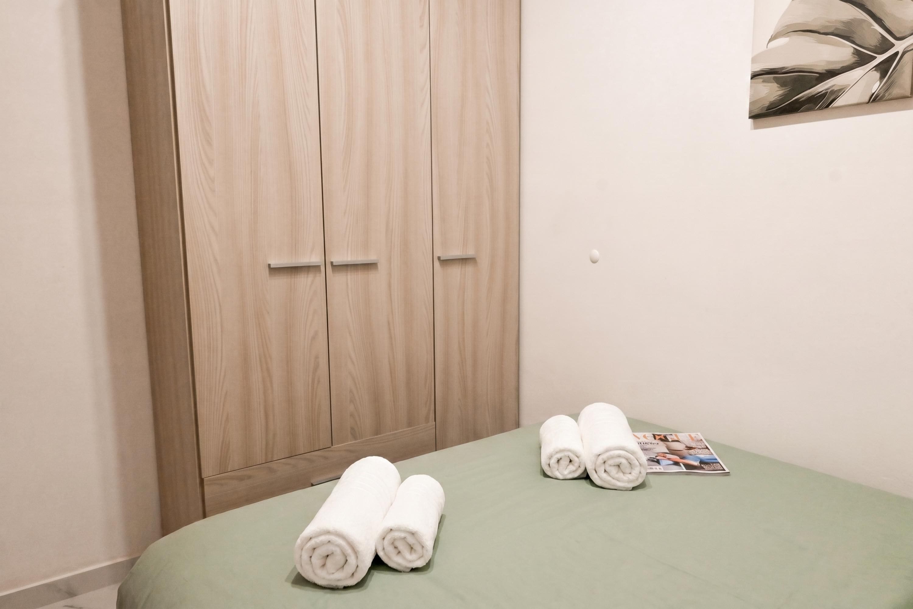 A room with a bed, a wooden wardrobe, and a magazine on the bed.
