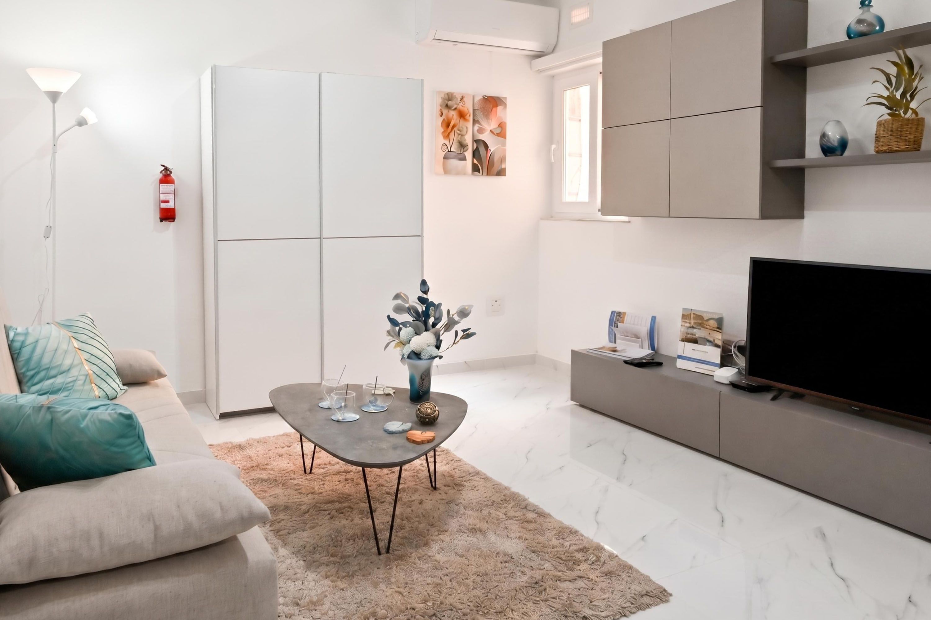 Una sala moderna con sofá, mesa de centro, televisor y elementos decorativos.