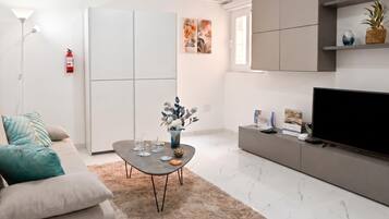 Una sala moderna con sofá, mesa de centro, televisor y elementos decorativos.
