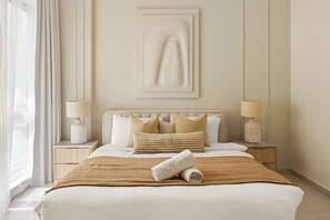 A hotel room with a bed, two bedside tables, a wall-mounted artwork, and a window with curtains. - Silkhaus Polo Residence 1BR 2 Baths Meydan (Dubai)