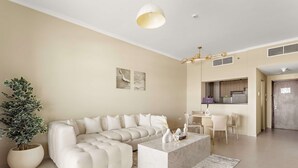 A modern living room with a sectional sofa, a marble coffee table, and a potted plant. - Silkhaus Ajwan 1BD Mamsha Beach Access (Abu Dhabi)