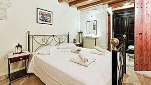 A bedroom with a bed, a nightstand, a mirror, a wooden door, and a framed picture on the wall. - Villa Poseidon - Superior Suite In Zante w Pool (Zakynthos)