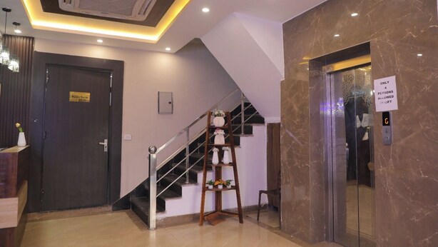 A modern hotel lobby with a staircase, an elevator, and a kitchen door. - The Royal Casa Hotel And Banquet (Ghaziabad)