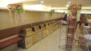 A hotel lobby with a long reception desk, a display of gold jewelry, and floral decorations. - The Royal Casa Hotel And Banquet (Ghaziabad)