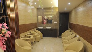 A spa area with wicker chairs, a sink, and a mirror. - The Royal Casa Hotel And Banquet (Ghaziabad)