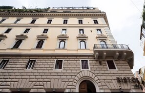 A multi-story building with a classical architectural style, featuring a prominent arched entrance and a balcony with wrought iron railings. - 'Rione Monti Charming Suite Colosseo' Apartment with Wi-Fi and Air Conditioning (Roma)