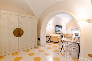 A room with a large wardrobe, a dining area with clear chairs, and a television. - 'Rione Monti Charming Suite Colosseo' Apartment with Wi-Fi and Air Conditioning (Roma)