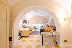 A room with a large arched doorway, a sofa, a table with chairs, and a patterned floor. - 'Rione Monti Charming Suite Colosseo' Apartment with Wi-Fi and Air Conditioning (Roma)