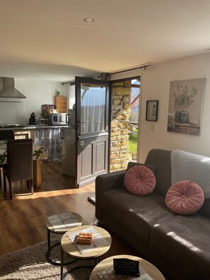 A cozy living room with a sofa, two coffee tables, and a dining area with a kitchen in the background. - Studio-Mountain view-Private Bathroom (Aleu)