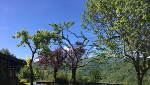Un espace de pique-nique avec des bancs et un bâtiment en pierre, situé dans un cadre boisé.