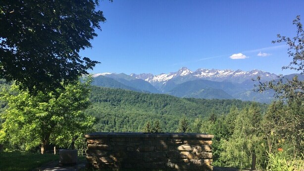 Un banc en pierre, situé dans un espace verdoyant, avec une montagne en arrière-plan.