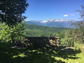 Un banc en pierre, situé dans un espace verdoyant, avec une montagne en arrière-plan.