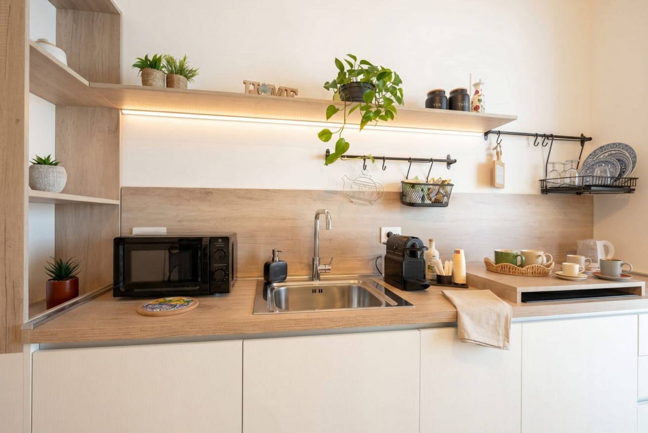 Eine moderne Küche mit Mikrowelle, Spüle und Holzregalen mit Pflanzen.