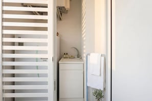 Un bagno compatto con lavandino, porta asciugamani e una piccola pianta in vaso.