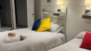 A hotel room with two beds, a wardrobe, a mirror, and a bedside table with a lamp. - Fabulous 2-bedroom apartment in NW8 London perfect for your stay (London)