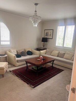 Ein Wohnzimmer mit einer Chandelier, zwei Sofas, einem Couchtisch, einer Lampe und einem Teppich.