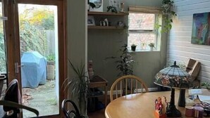 A dining area with a round table, chairs, a hanging lamp, and a view of the backyard through a glass door. - Stylish Family Home with Garden near Tottenham Stadium & Easy Central Access (London)