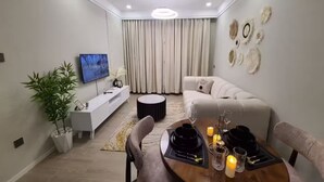 Una sala de estar moderna con sofá, mesa de comedor, televisor y decoración en la pared.