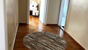 Ein Flur mit Holzboden, Teppich und einem Bett im Hintergrund.