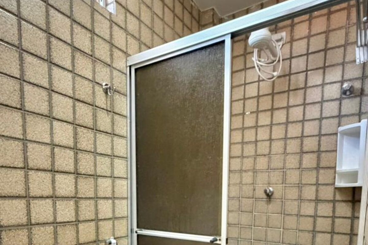Un baño pequeño con inodoro, cabina de ducha y pared de azulejos.
