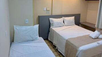 A hotel room with two single beds, a small bathroom, and a tiled floor.