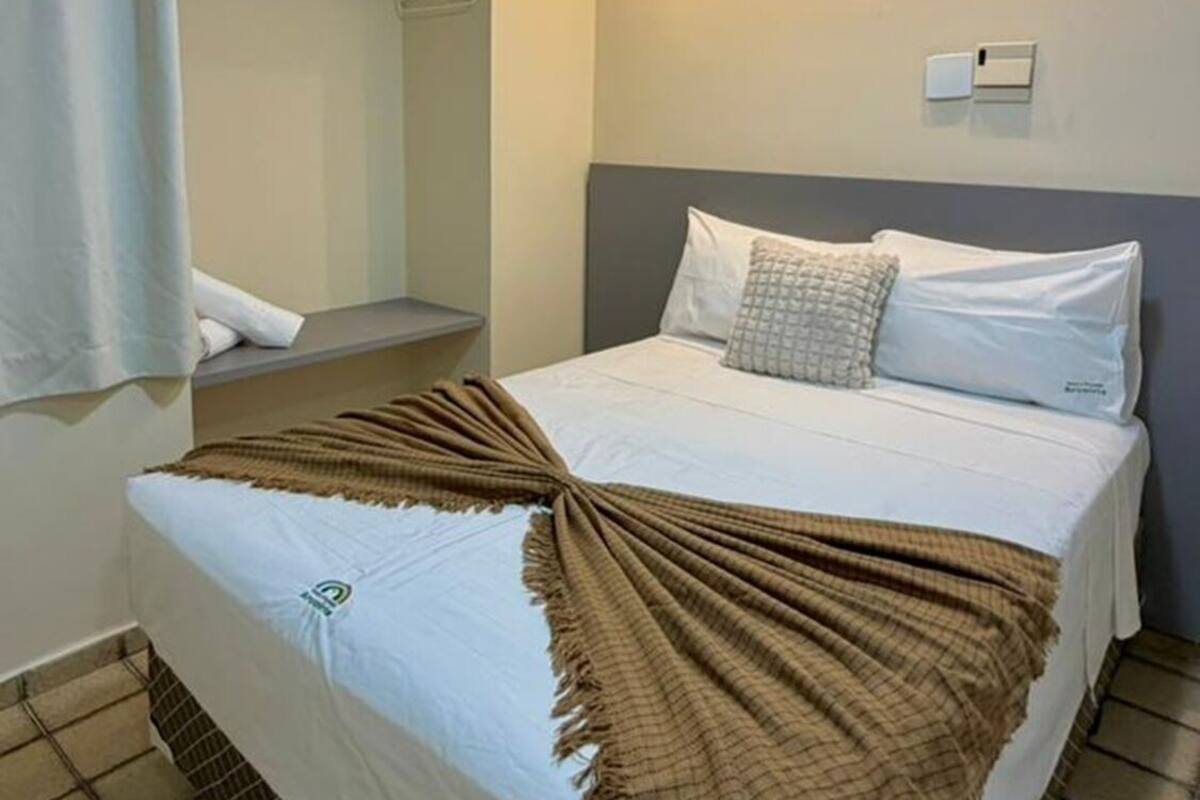 A hotel room with a bed, a wardrobe, a bathroom, and a ceiling light.