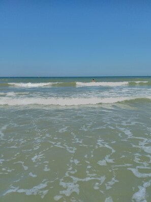 A beach with waves and a clear sky.