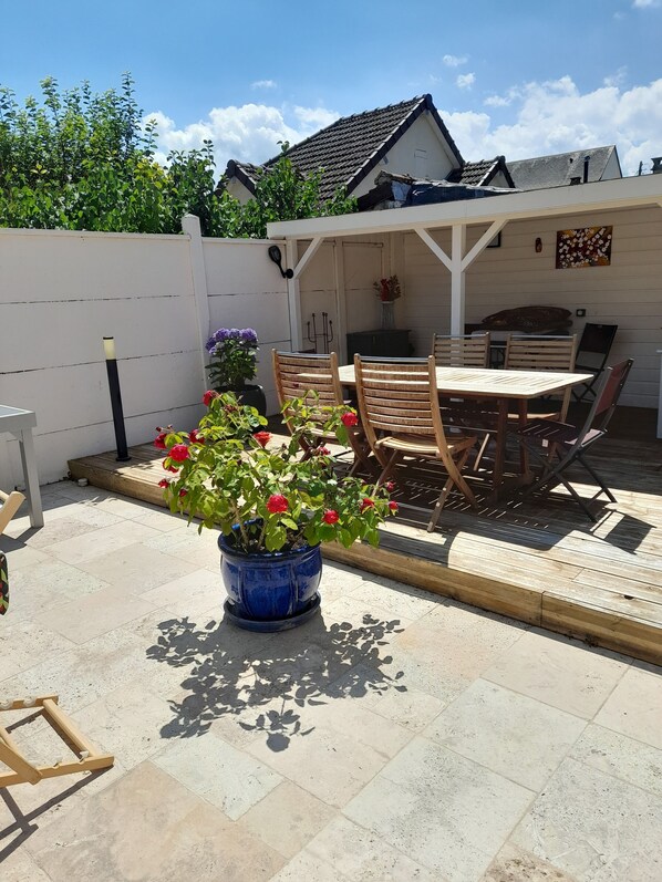 A patio with a table and chairs, a potted plant, and a barbecue grill.
