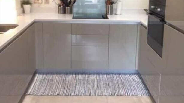 Uma cozinha moderna com uma ilha central, armários embutidos e micro-ondas.