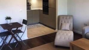 Uma sala de estar moderna com área de jantar, cozinha ao fundo e uma janela grande.