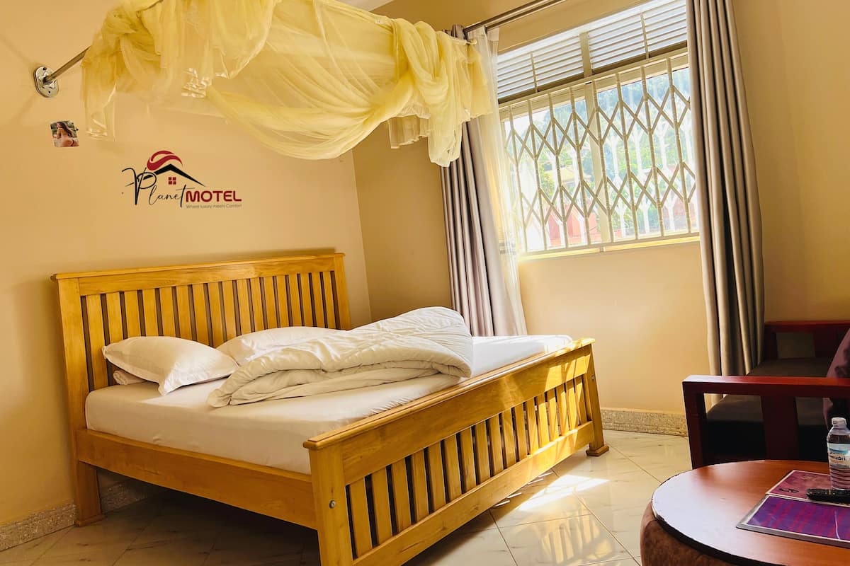 A bed with a wooden headboard, a canopy, and a window with curtains.