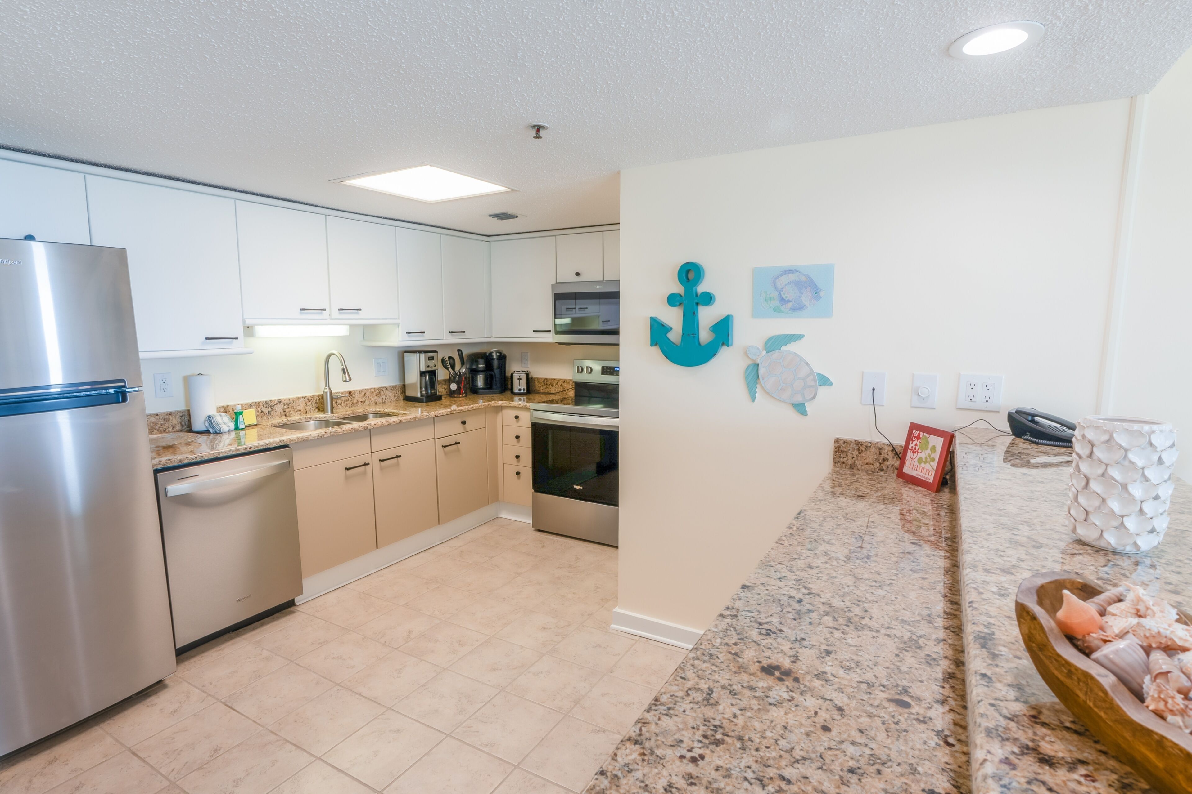 A modern kitchen with white cabinets, stainless steel appliances, and a granite countertop.
