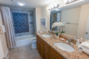 A bathroom with a shower, two sinks, a mirror, and a toilet. - 329 North Hampton, Expansive Balcony & Resort Amenities 2 Bedroom Condo (Myrtle Beach)