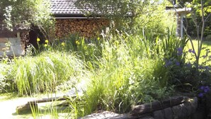 Un jardín con hierba alta, un muro de piedra y un edificio con tejado de tejas.