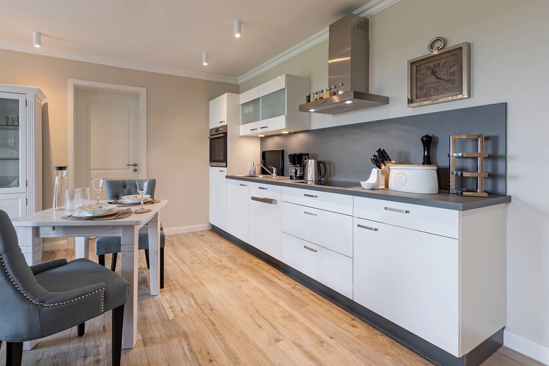 A modern kitchen with white cabinets, a built-in oven, and a coffee maker.