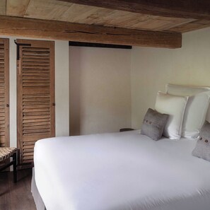 Un dormitorio con una cama grande, persianas de madera y una silla de mimbre.