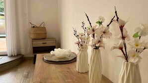 Une table en bois, surmontée de vases blancs et d’un panier tressé, posée sur un plancher en bois.