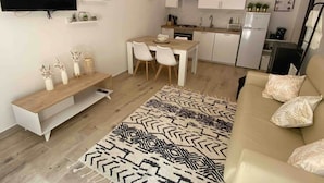 Un espace de vie moderne comprenant un téléviseur à écran plat, un coin repas, une cuisine et un canapé.